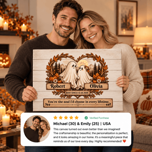 A couple holds up a personalized wooden canvas print in a cozy living room setting. The canvas features a rustic wood-grain design with two cartoon ghosts, autumn leaves, pumpkins, and custom names 'Robert' and 'Olivia' with '100th Birthday' text.