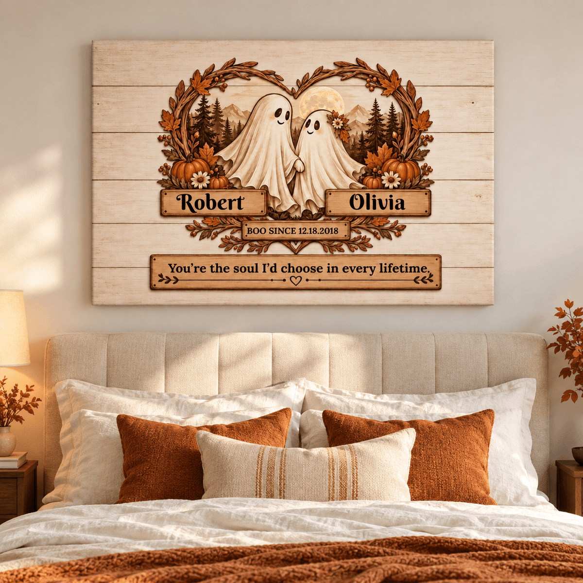 Personalized wooden wall art hanging above a bed, featuring two ghost figures with a heart-shaped wreath, pumpkins, trees, and custom names Robert and Olivia with a memorial-style quote.
