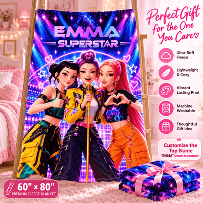 A custom fleece blanket featuring three cartoon-style rock stars with the text 'EMMA SUPERSTAR' is displayed on an easel in a bedroom setting. A folded matching blanket with a pink ribbon is shown in the foreground, and a list of product features is displayed on the right side.