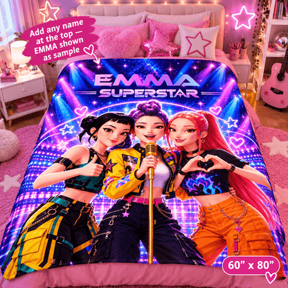 A colorful bedding set featuring a printed comforter or duvet with three cartoon female singers and the text 'EMMA SUPERSTAR' on a bed in a pink bedroom. The bedding includes a matching pink pillow shams and pillows, and the image includes promotional text overlays indicating size 60" x 80" and customizable name placement.