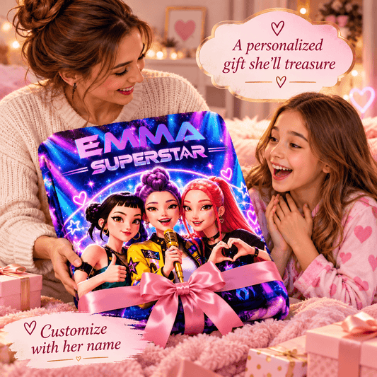 A woman and a young girl are smiling while holding a large personalized gift box featuring cartoon characters and the text 'EMMA SUPERSTAR.' The box is wrapped in a pink ribbon and bow, with cozy home decor in the background and text overlays that say 'A personalized gift she'll treasure' and 'Customize with her name.