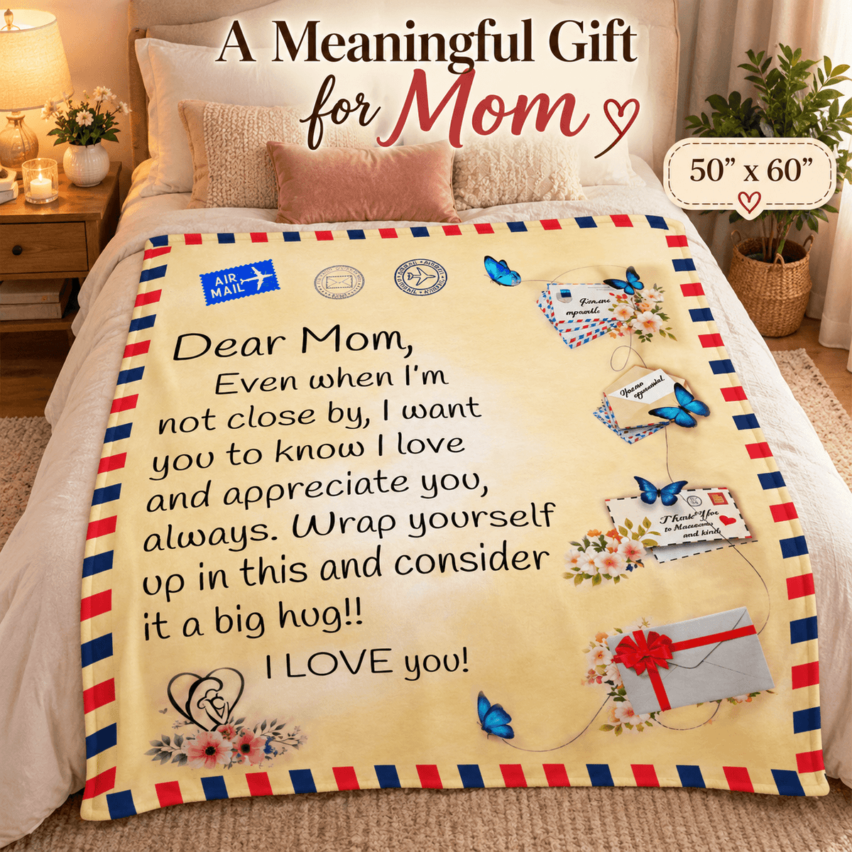 A fleece blanket with a sentimental message for Mom, styled on a bed in a cozy bedroom setting. The blanket features a cream background with a red, white, and blue striped border, decorated with illustrations of blue butterflies, flowers, and postmarks.
