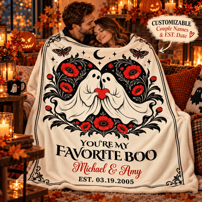 A couple wrapped in a cozy fleece blanket featuring a Halloween-themed design with two ghosts, red flowers, black scrollwork, and the text 'YOU'RE MY FAVORITE BOO Michael & Amy EST. 03.