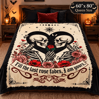 A gothic-themed bedding set featuring a cream-colored blanket with a black skeleton heart, red roses, and the quote 'Till the last rose fades, I am yours.' The blanket is styled on a bed in a cozy, dimly lit bedroom with bedside tables, candles, and a pumpkin lantern.