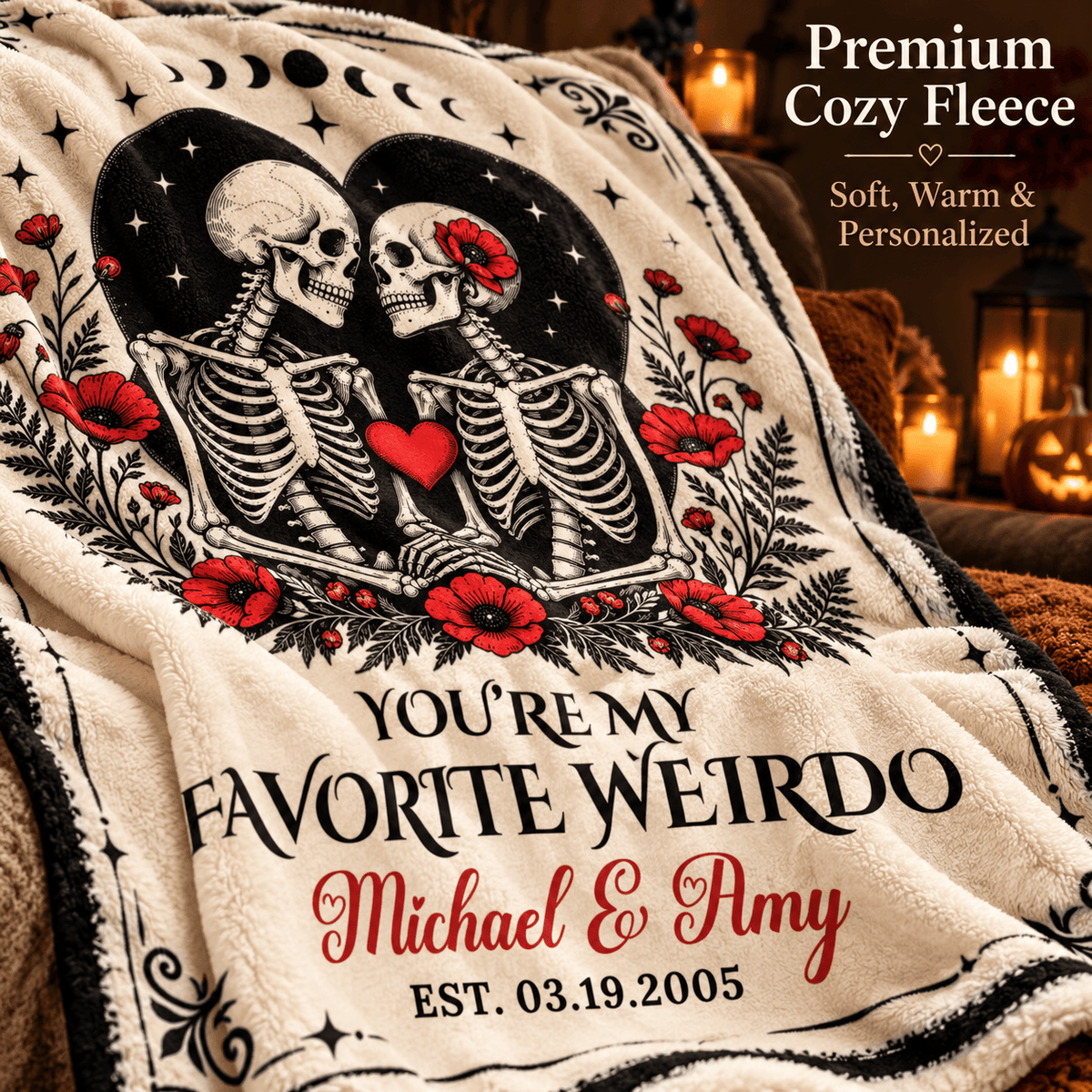 A personalized cream-colored fleece throw blanket draped over a couch, featuring a black-and-white skeleton illustration with red poppies, a red heart, and custom text reading 'YOU'RE MY FAVORITE WEIRDO Michael & Amy EST. 03.