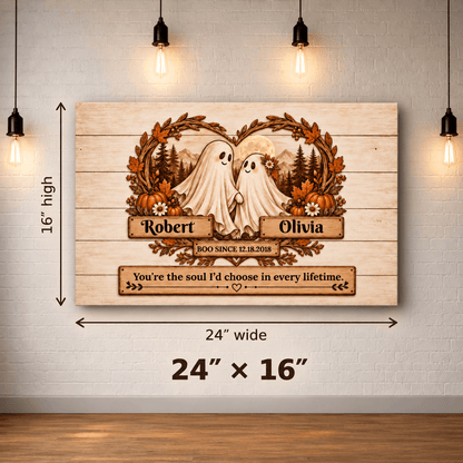 Personalized wooden ghost canvas wall art displayed on a white brick wall with hanging bulbs. The artwork shows two white ghosts under a floral wreath with autumn leaves and trees, with names Robert and Olivia and a quote.