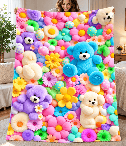 A person holds up a large blanket or throw featuring a colorful, playful pattern of 3D-effect fluffy teddy bears and bright flowers in pink, blue, yellow, purple, green, and orange, set against a cozy bedroom background.
